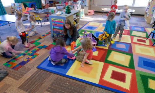 childcare room with staff and kids playing
