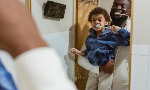 Dad holding son looking in mirror to brush teeth