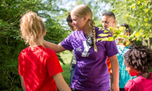 Teen staff member with campers on a trail.