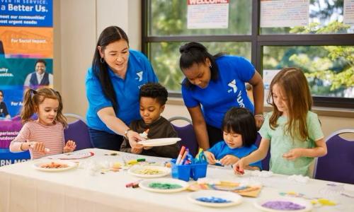 Female YMCA staff in blue shirts teaching children