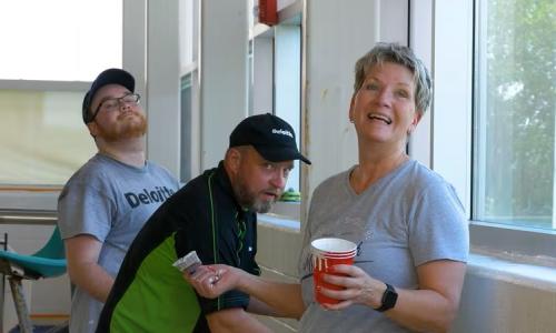 Volunteers smile at the camera while painting