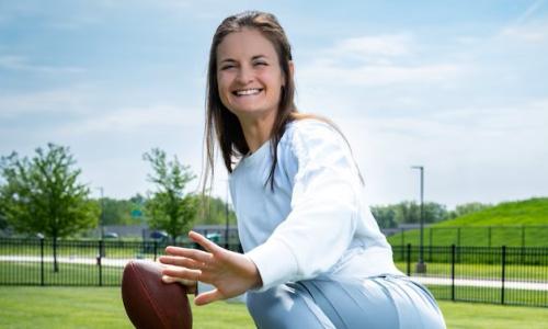 Hannah Bartlome in Heisman position with football