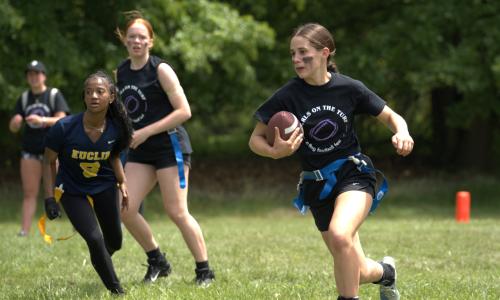Girl running with football towards the endzone