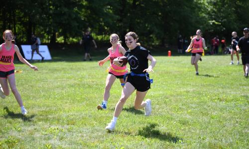 Girl running with football scoring a touchdown