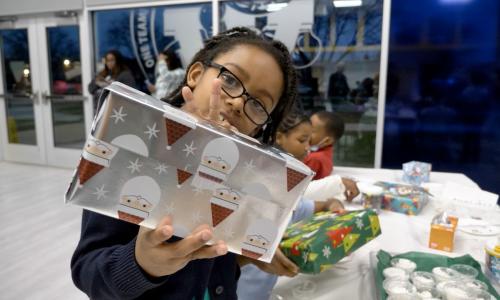 Child holds a Christmas present at YMCA's Holiday Camp