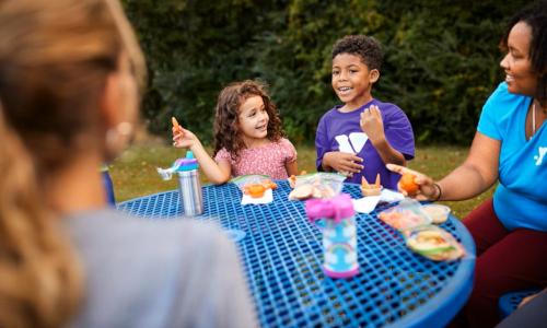 Campers and camp staff eat lunch outside