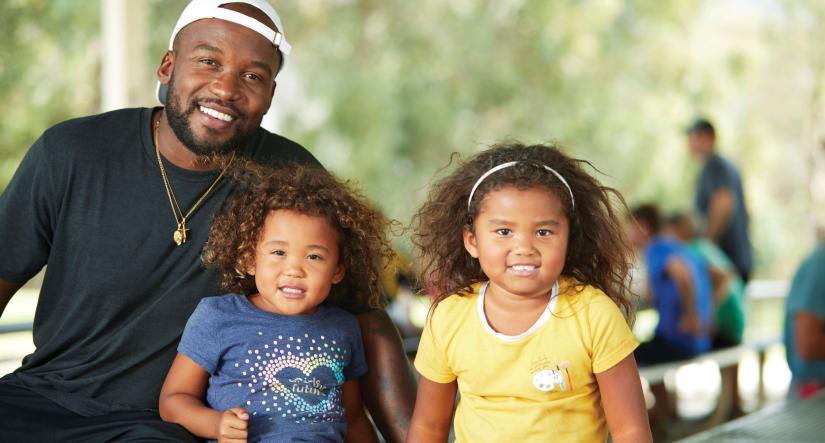 father with his two daughters smiling at a picnic table