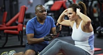 A personal trainer guides a woman doing sit ups