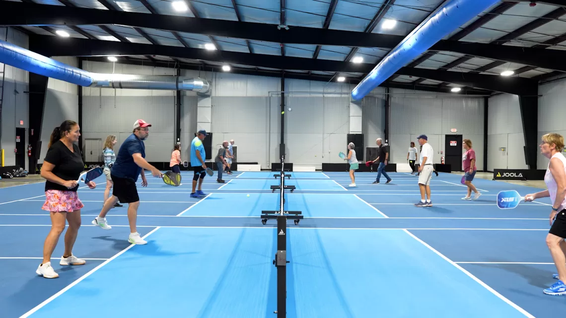 People playing pickleball on blue courts with athletic wear.