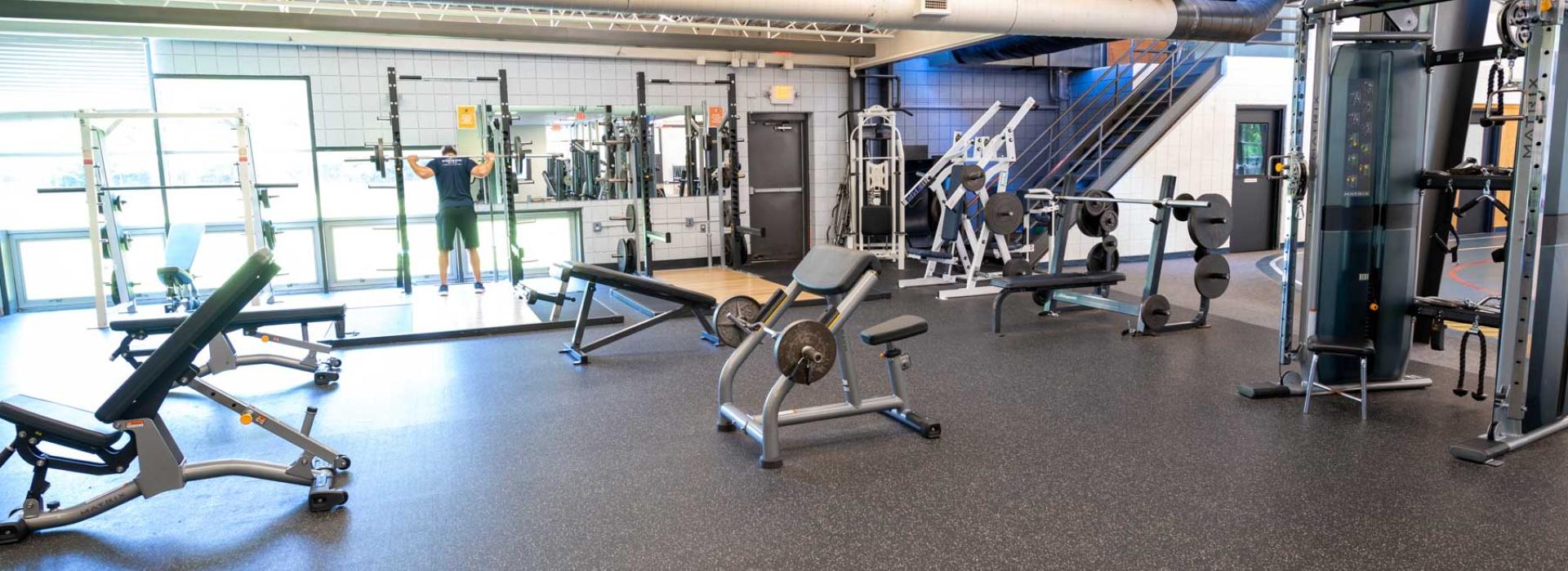 weight room with various free weight machines and benches