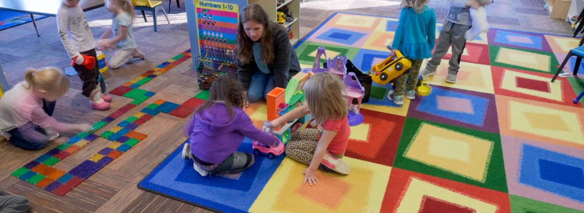 childcare room with staff and kids playing